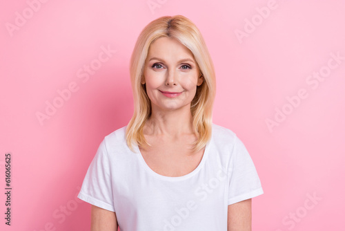 Portrait of senior woman blonde hairstyle wearing trendy white t-shirt no print smiling cute wellness isolated on pink color background