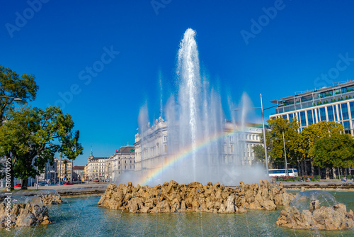 Cityscape of Vienna, Austria. Fountain called Hochstrahlbrunnen with high water jet, rainbow and blue sky at historical downtown of the city, Schwarzenberg Square.