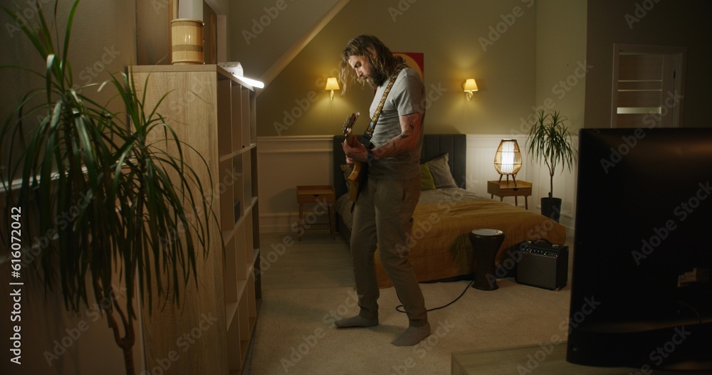 Fototapeta premium Man plays guitar in bedroom.