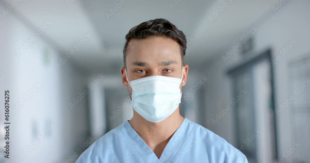 Portrait of happy biracial male doctor wearing face mask, slow motion Portrait of happy biracial male doctor wearing face mask, slow motion