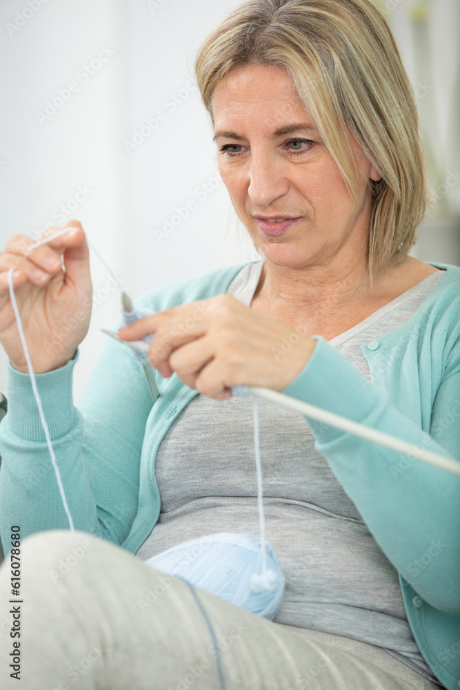 Fototapeta premium serious concentrated retired lady holding needles and yarn