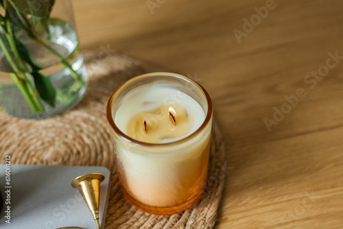 Home cozy interior. Candles, a bouquet of peonies in a glass vase on a wooden coffee table. Spring.