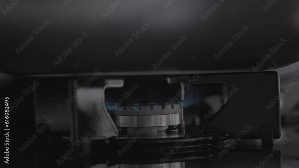 In slow motion, the gas burner on the black stove ignites, with a large pot placed on it. In slow motion, the gas burner on the black stove ignites, with a large pot placed on it.