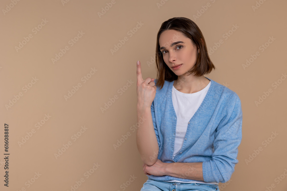 Attractive woman in casual clothing showing number one with finger Attractive woman in casual clothing showing number one with finger
