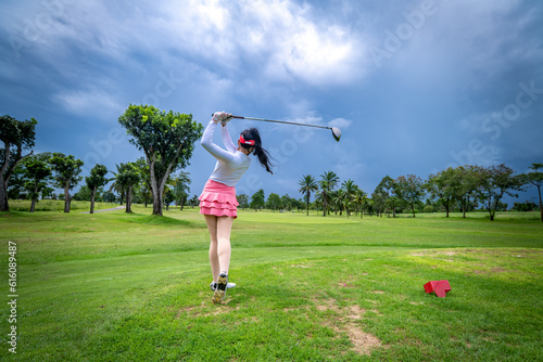 Professional woman golfer teeing to hole in player tournament competition at golf course for winner with green golf background.	
