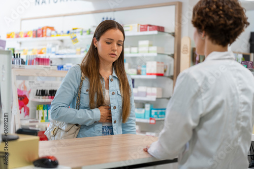Young woman with a stomachache in a pharmacy photo