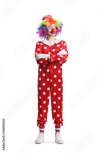 Full length portrait of a clown standing with folded arms