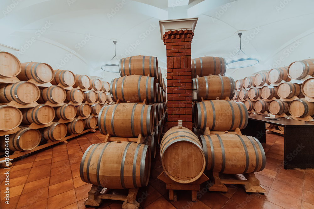 Wine or cognac barrels in the cellar of the winery, Wooden wine barrels in perspective. Wine vaults.Vintage oak barrels of craft beer or brandy. 