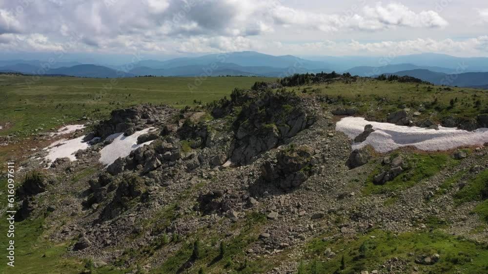 Aerial video of mount Sarlyk slopes. Drone flies along slope with snowfield and rocks. Altai highlands. Aerial video of mount Sarlyk slopes. Drone flies along slope with snowfield and rocks. Altai highlands.