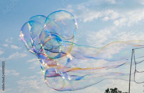 Soap bubbles in the blue sky. Beautifully iridescent balls of soap foam in the air. Background and wallpaper.
