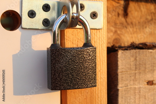 metal padlock on the door of a wooden shed