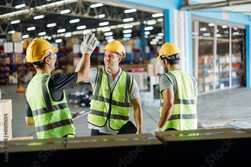 Three warehouse workers using a digital tablet while recording inventory. Logistics employees working with warehouse management software in a large distribution centre.