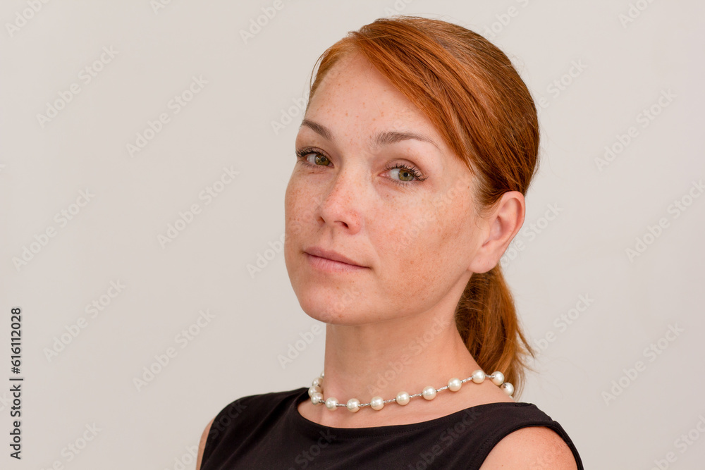 Portrait of caucasian middle aged woman face with freckles wearing black dress and pearl beads on white background Portrait of caucasian middle aged woman face with freckles wearing black dress and pearl beads on white background