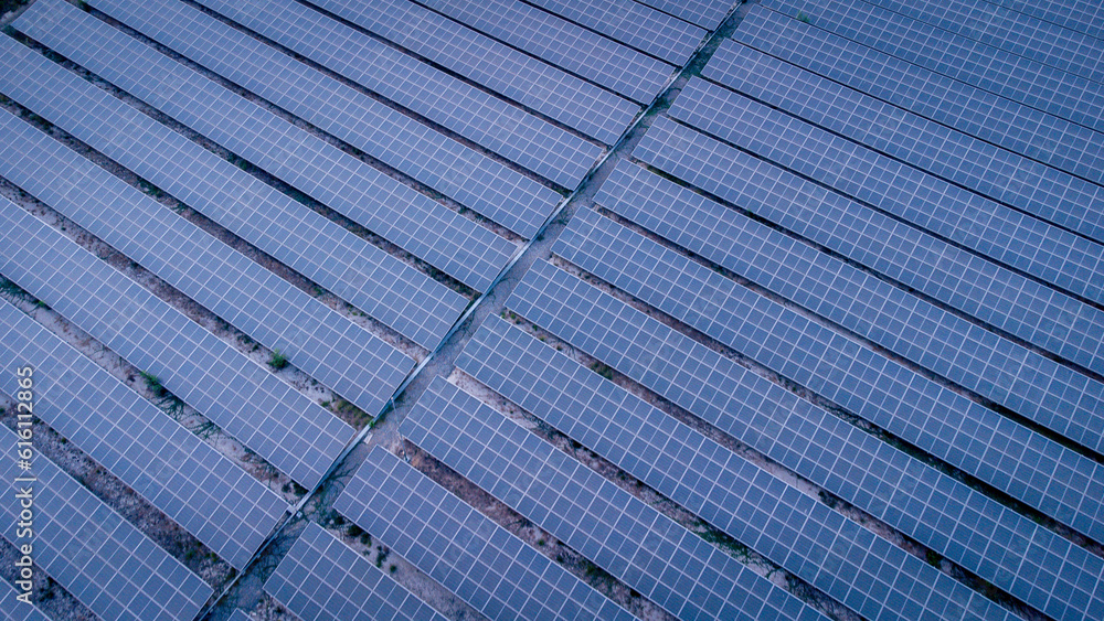 Future green energy and sustainable electricity resource concept. Outdoor focus on solar panels on rooftops or photovoltaics of factories by drone. Industrial roof with solar cell grid with blue tone.