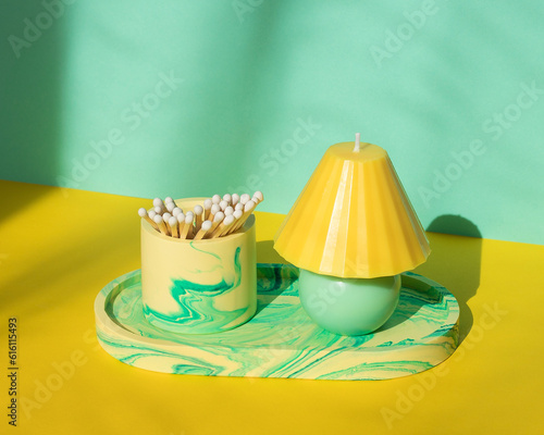 An oval tray with a glass with matches and a candle in yellow-green colors.