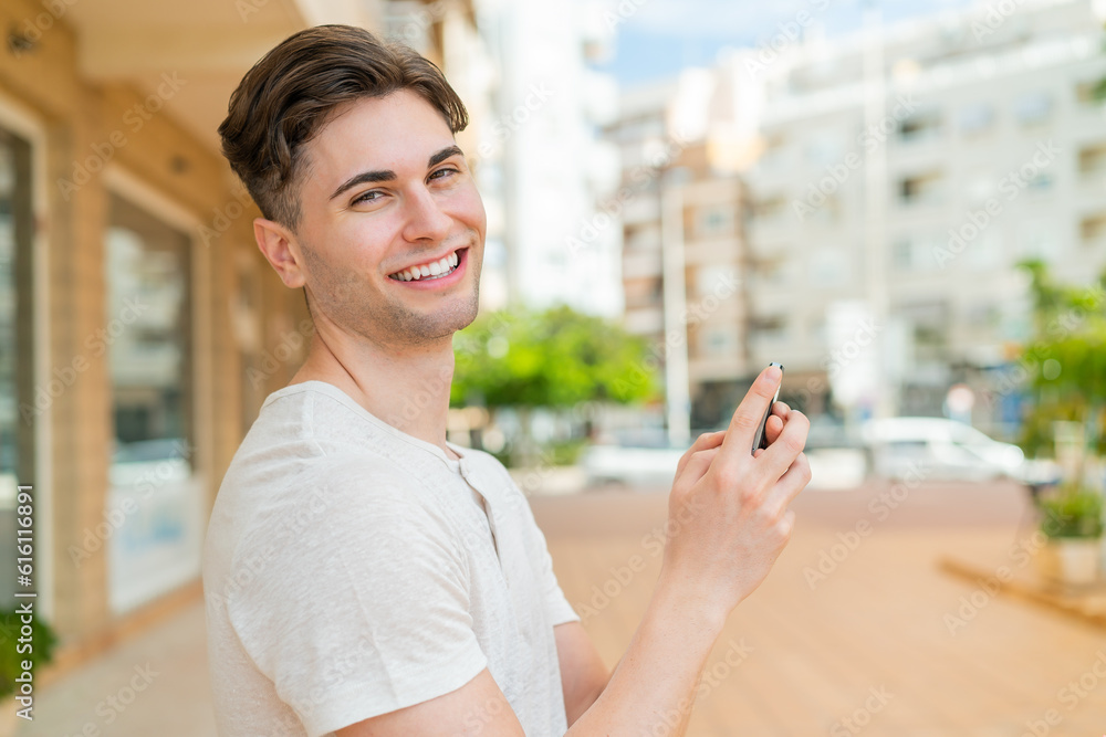 Young handsome man sending a message or email with the mobile Young handsome man sending a message or email with the mobile