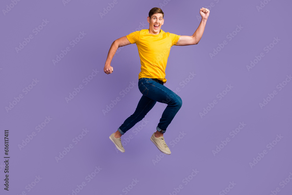 Full length body size view of attractive cheerful active guy jumping running isolated over purple color background