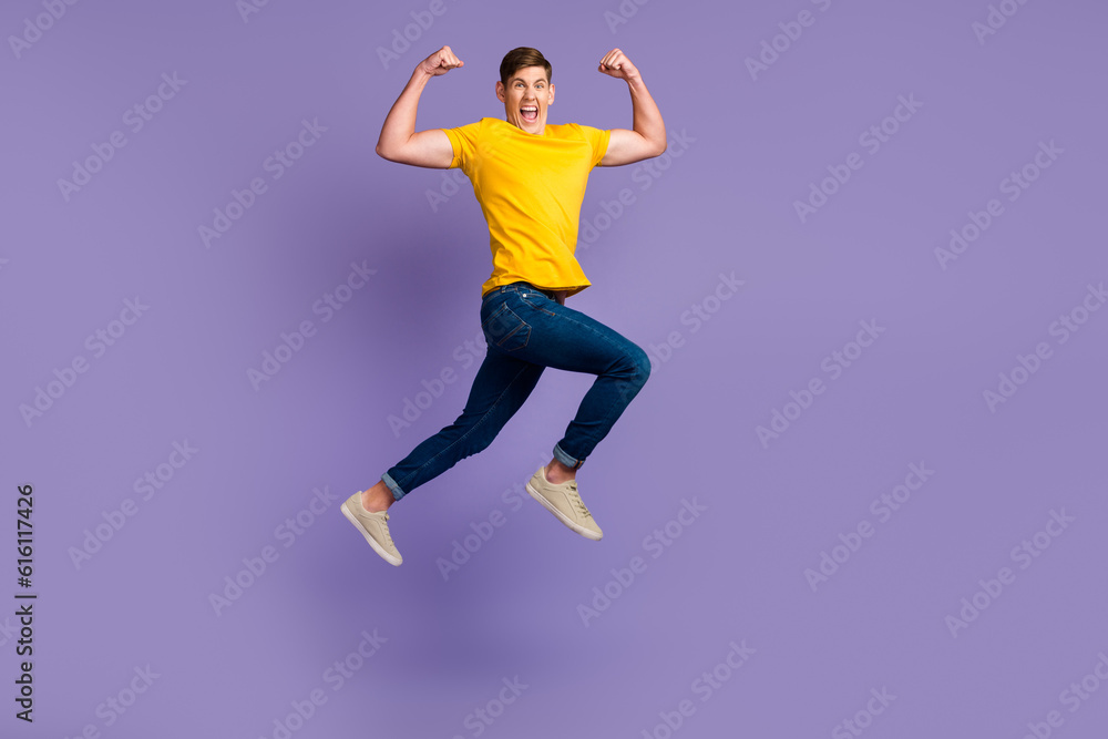 Full length of attractive active guy jumping up running fists raised air isolated over violet color background Full length of attractive active guy jumping up running fists raised air isolated over violet color background