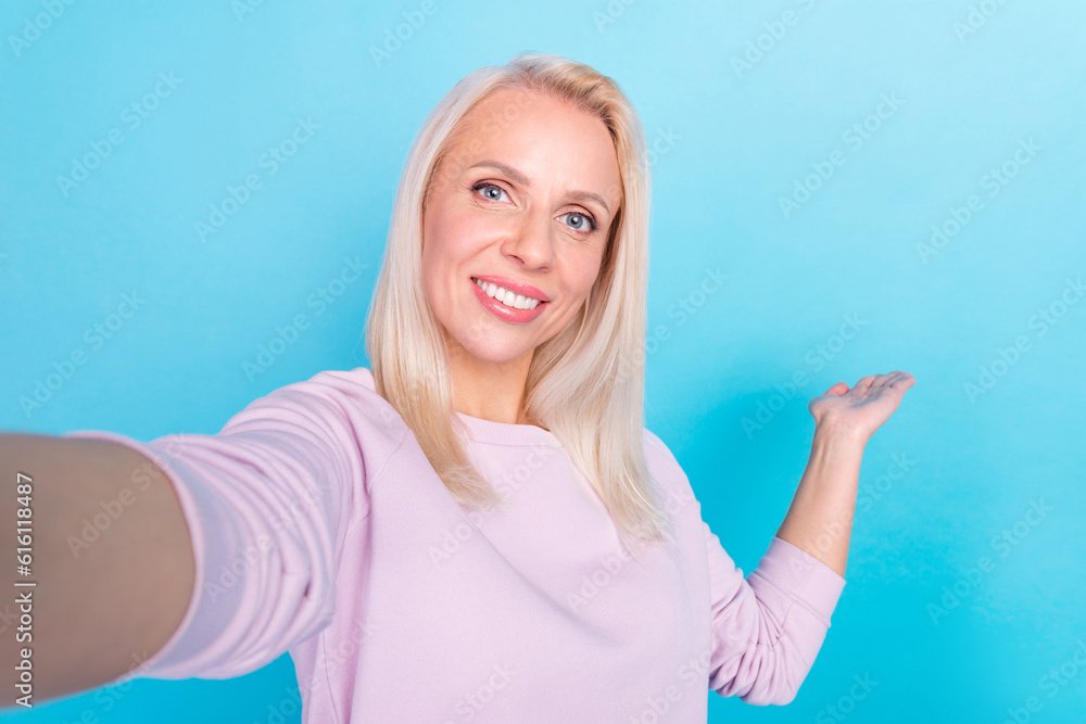 Fototapeta premium Selfie portrait of cheerful mature woman wearing light pink blouse video call online blog show mockup isolated on blue background