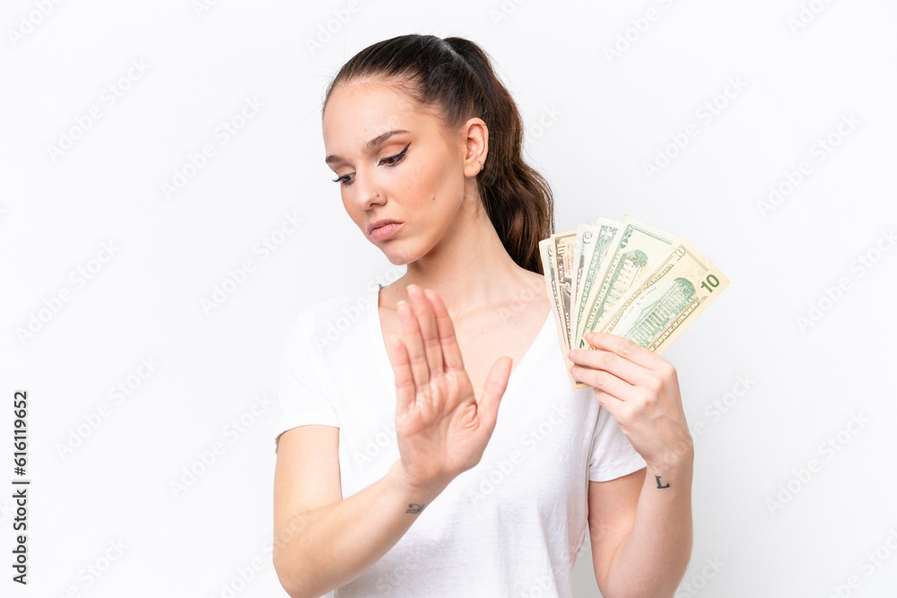 Young caucasian woman taking a lot of money isolated on white background making stop gesture and disappointed Young caucasian woman taking a lot of money isolated on white background making stop gesture and disappointed