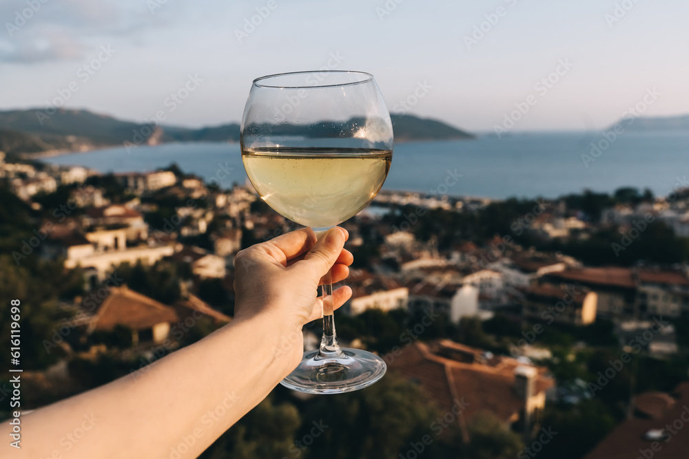 Obraz premium White wine in glass, view of sunset town.