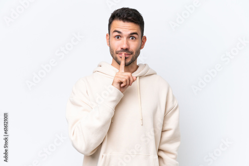 Young caucasian man isolated on white background showing a sign of silence gesture putting finger in mouth