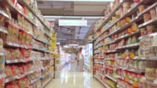 Blurred and trolley moving through people and product shelf within supermarket