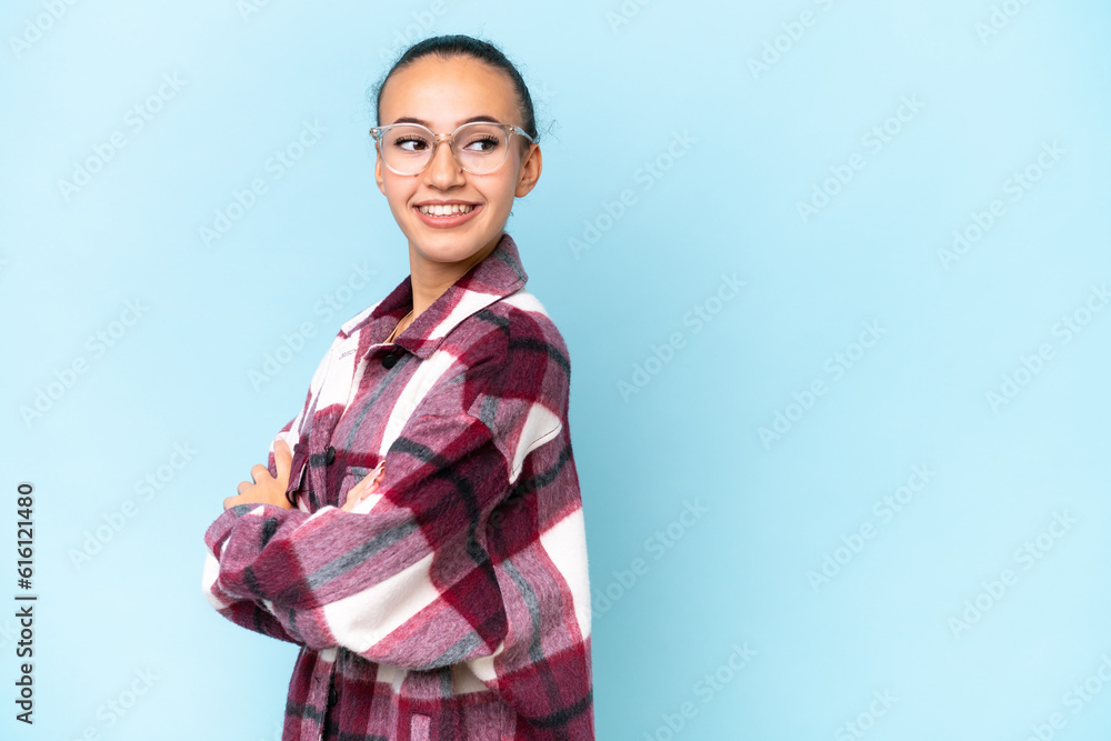 Young Arab woman isolated on blue background with arms crossed and happy Young Arab woman isolated on blue background with arms crossed and happy