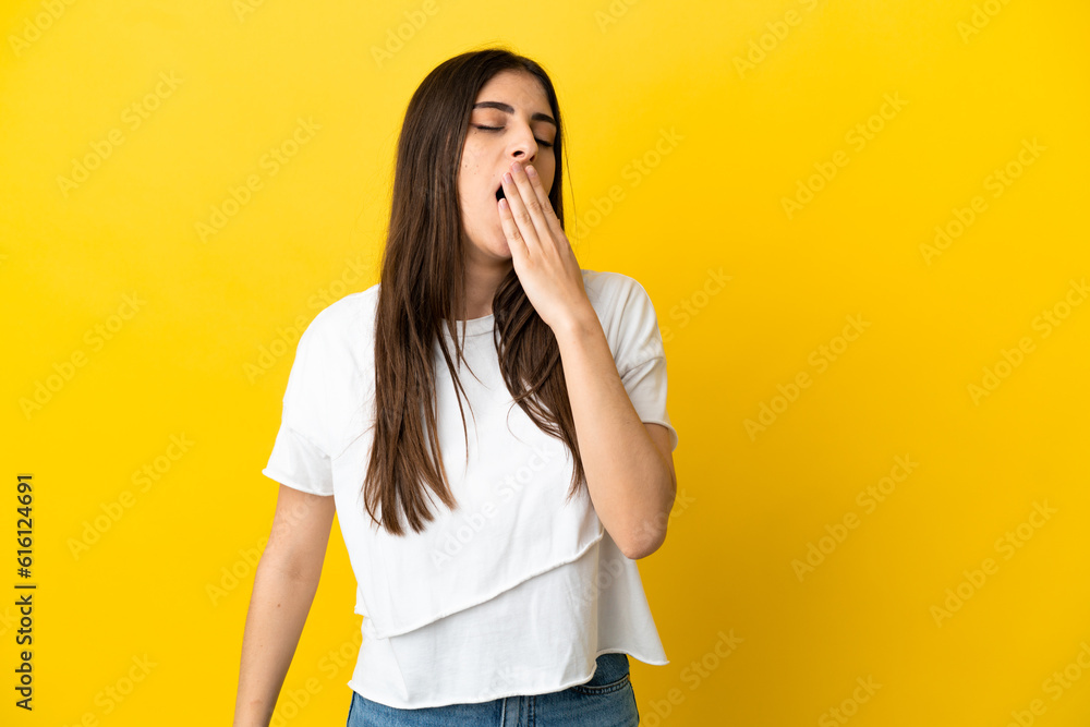 Young caucasian woman isolated on yellow background yawning and covering wide open mouth with hand Young caucasian woman isolated on yellow background yawning and covering wide open mouth with hand