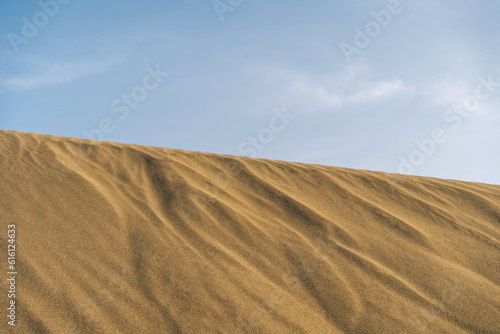 Desert sand hill with wavy sand texture, blu sky.
