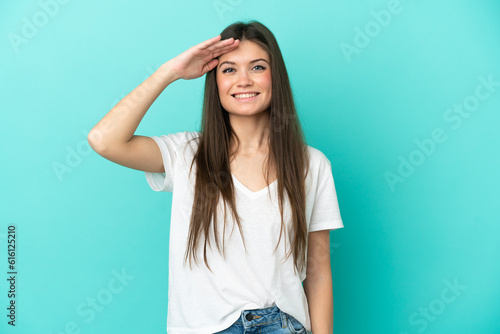Young caucasian woman isolated on blue background saluting with hand with happy expression