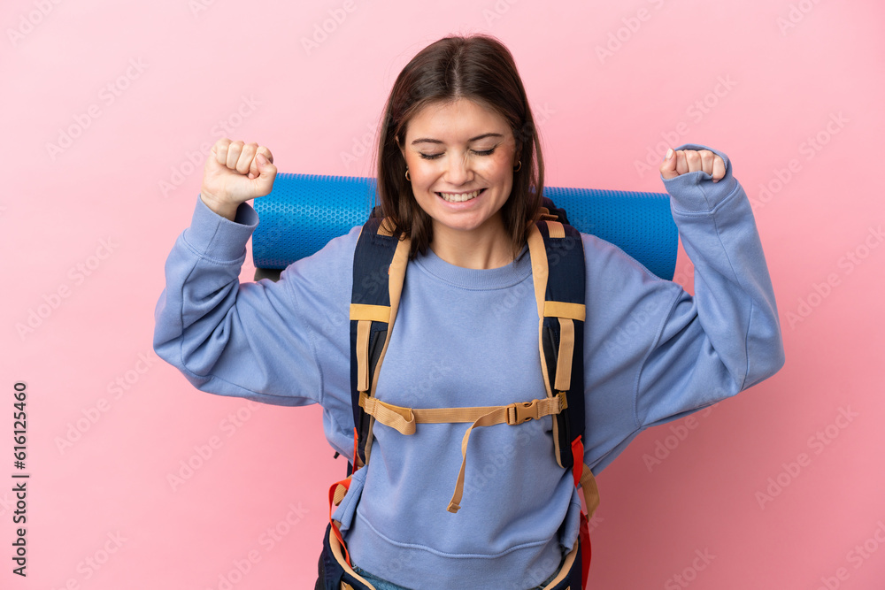 Young mountaineer woman with a big backpack isolated on pink background doing strong gesture Young mountaineer woman with a big backpack isolated on pink background doing strong gesture