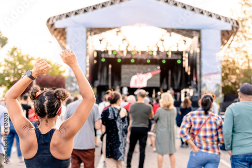 Multiethnic young people enjoying a summer music festival concert of the stage at sunset