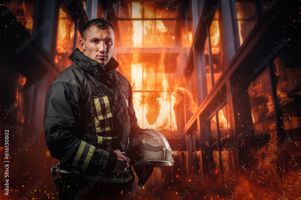 Courageous firefighter in protective uniform stands amidst billowing flames and smoke inside an office building. This photo exemplifies the bravery and sacrifice of emergency responders