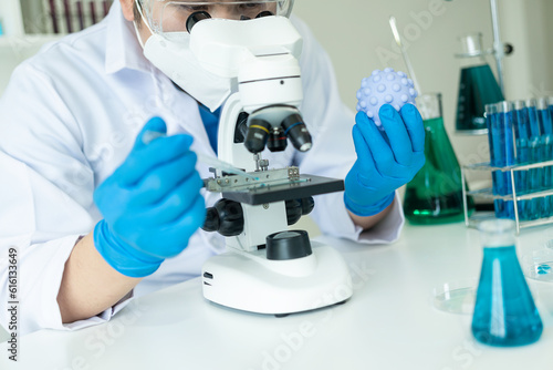 A gloved scientist pours blue acid into a test tube with clear liquid. Scientific research in the chemical industry The doctor examines the analysis in a test tube with a microscope.