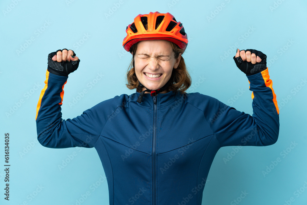 Young cyclist woman isolated on blue background doing strong gesture Young cyclist woman isolated on blue background doing strong gesture