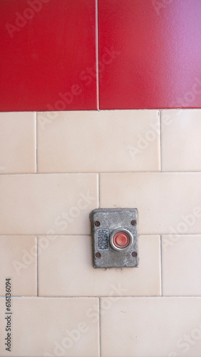 Botón rojo retro en pared de baldosa