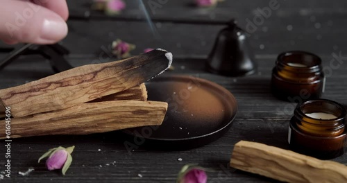 Burning Palo Santo stick, hand putting Palo Santo stick on wooden pile, aromatic scented wood placed on ceramic plate, bursera graveolens, Mexican Holy stick, close up footage, 4k relaxation video photo