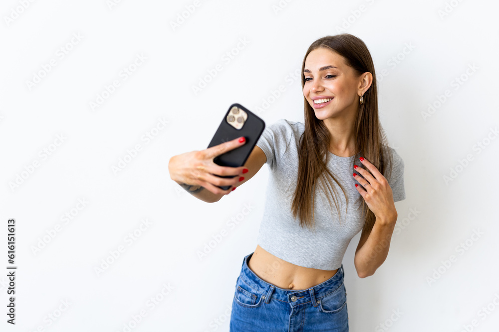 Φωτογραφία Portrait of a smiling woman making selfie photo on smartphone isolated on a whit