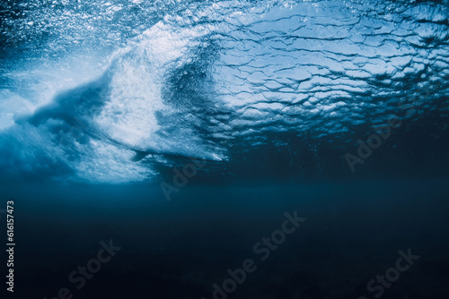 Wave underwater and surfer on surfboard in ocean. Underwater crashing wave and surfboard in transparent water
