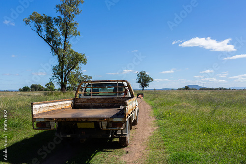 Sunlit ute driving up farm driveway through paddocks on australian farm photo