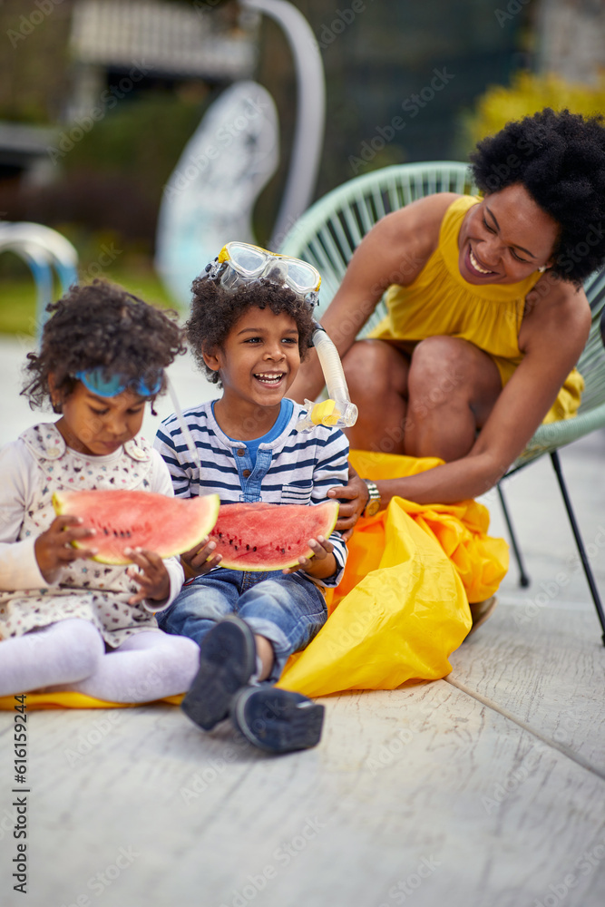 Fototapeta premium Summer Bliss: A Mother and Her Kids Enjoying Watermelon Delights Poolside