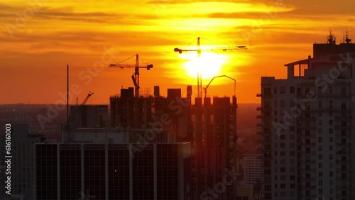 New construction site of developing residense in american urban area at sunset. Industrial tower lifting cranes in Miami, Florida. Concept of housing growth in the USA photo
