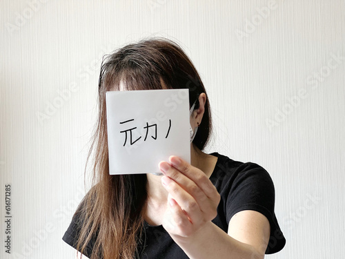 顔の前で元カノの文字入り紙を片手で持つ女性 photo