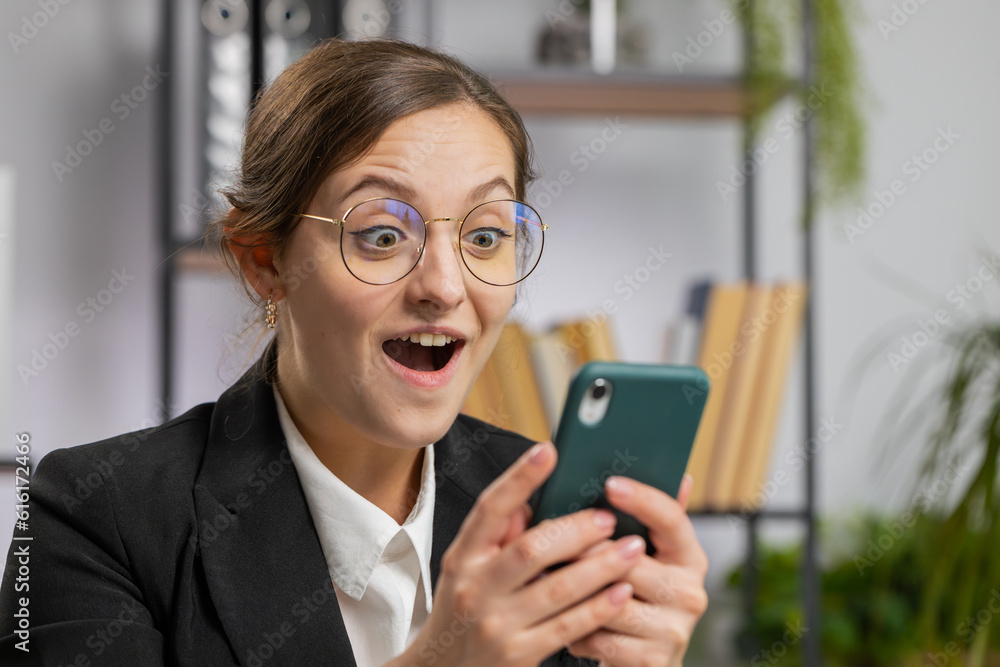 Oh my God, Wow. Happy amazed young Caucasian business woman working on smartphone shocked by sudden victory, game winning, lottery goal achievemen good news. Pretty manager girl freelancer at office Oh my God, Wow. Happy amazed young Caucasian business woman working on smartphone shocked by sudden victory, game winning, lottery goal achievemen good news. Pretty manager girl freelancer at office