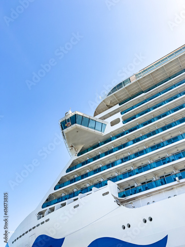 Cruise ship control room. Passenger craft concept: Looking up on high nautical vessel from port on sunny day. Many hotel rooms with sea view balconies, seperated by blue glass. Adventure travelling © Stockwars