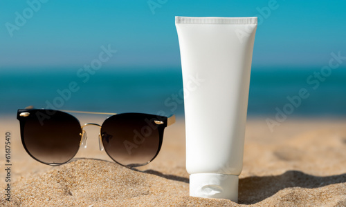 Mocup of sunscreen on beach sand with blurred sea background. © wesleyyaya