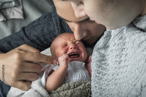 Newborn baby colic close up. Young parents and crying baby 1 month old photo