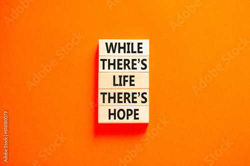 Life and hope symbol. Concept word While there is life there is hope on wooden block. Beautiful orange table orange background. Business lifestyle life and hope concept. Copy space.