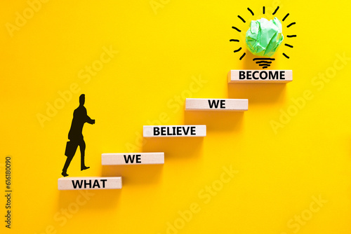 We become or believe symbol. Concept word What we believe We become on wooden block. Beautiful yellow table yellow background. Businessman icon. Business we become or believe concept. Copy space.